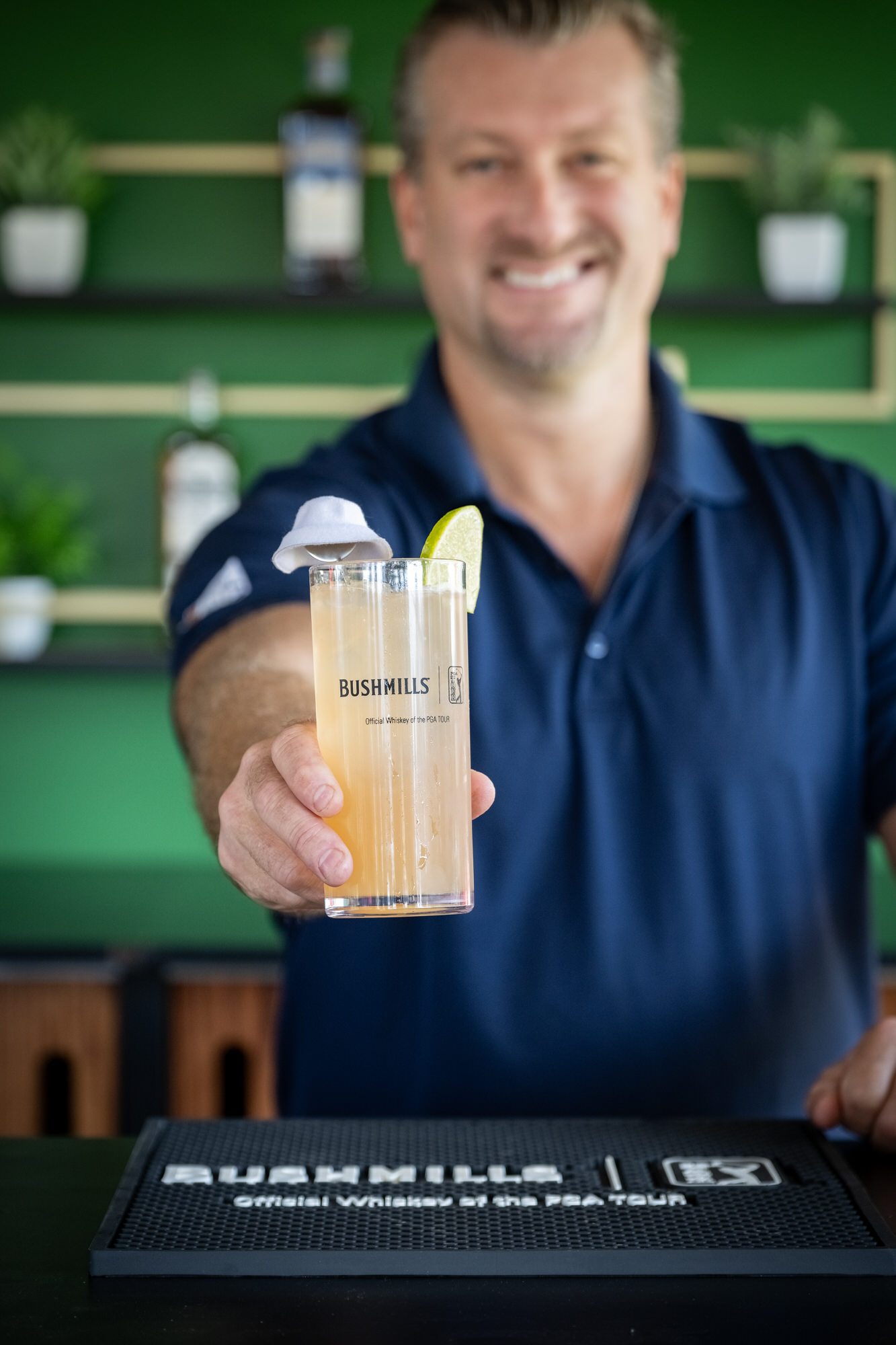 Smiling bartender handing over a cocktail at a sponsor bar