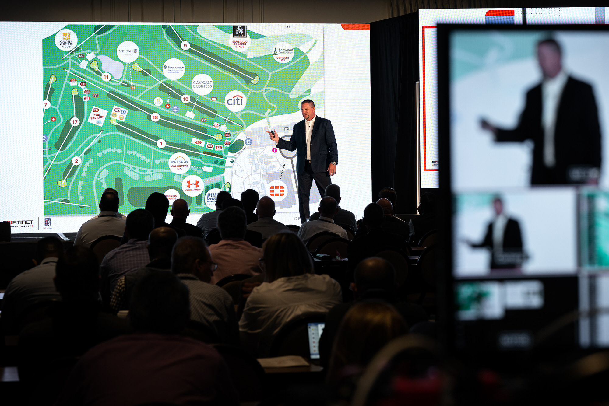 Presenter walking a seated audience through a map on the main screen