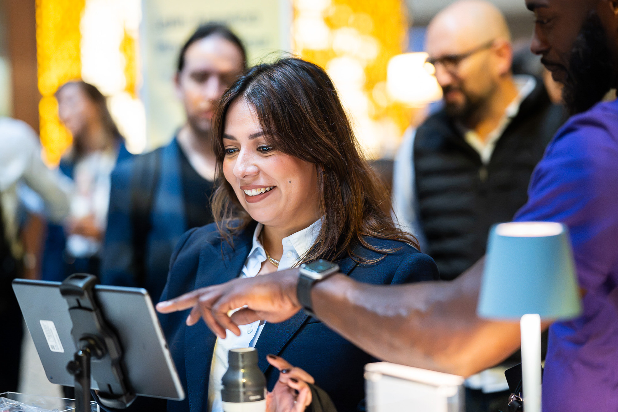 Smiling staff member checking in attendees on a tablet