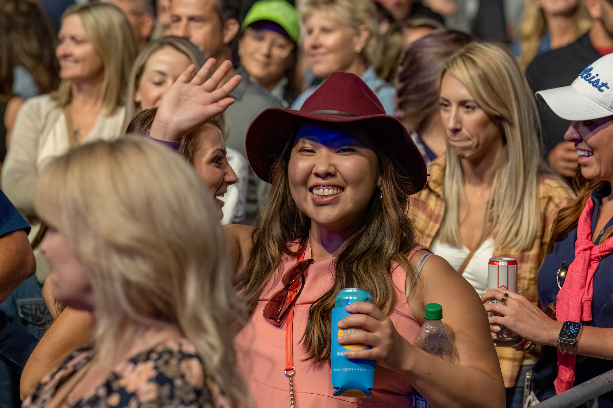 Fans smiling and waving near the front of a concert crowd