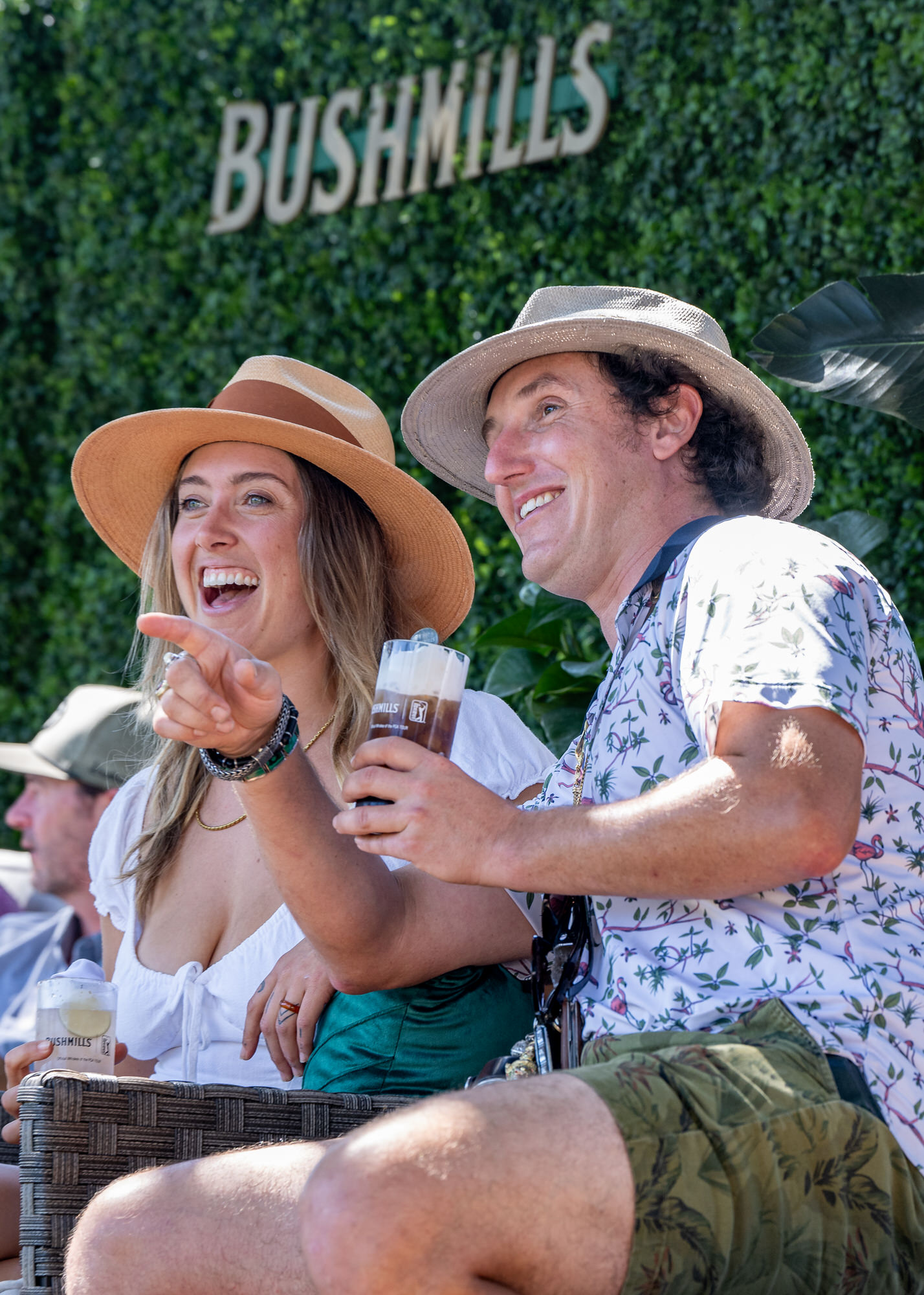 Guests in sun hats laughing and pointing from a sponsor lounge