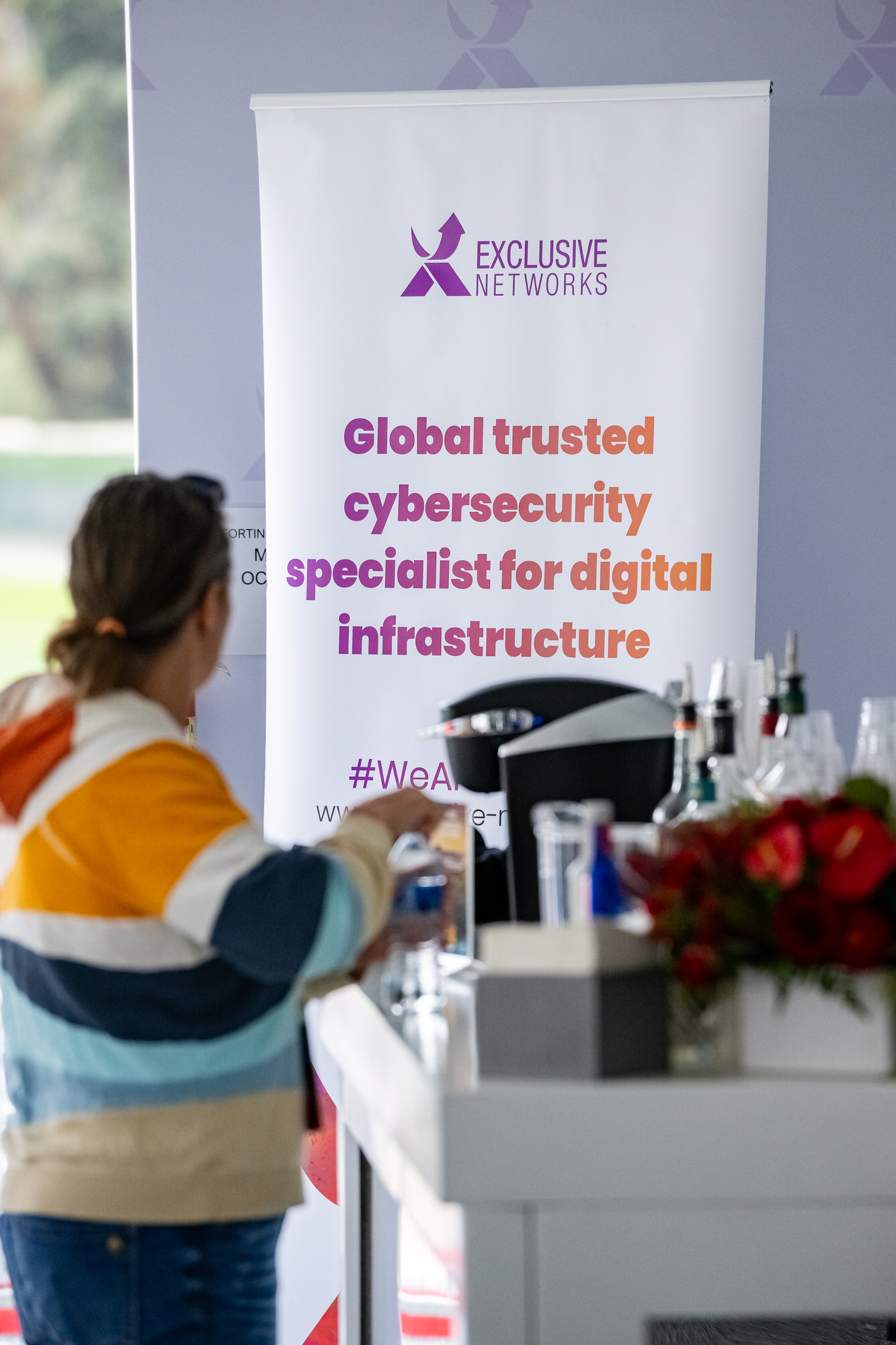 Guest at a drink station beside a sponsor banner in a hospitality tent