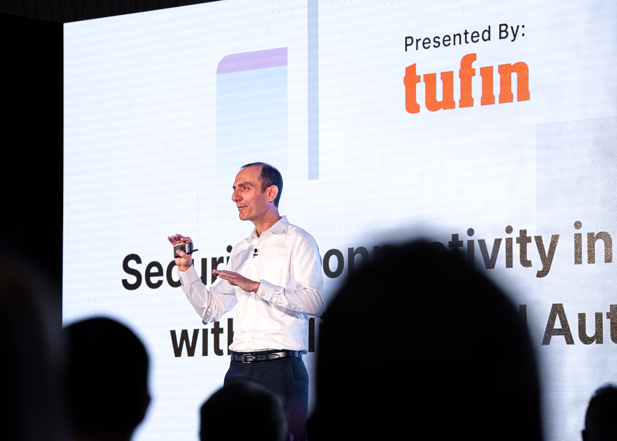 Keynote speaker presenting in front of a bright screen, audience in silhouette