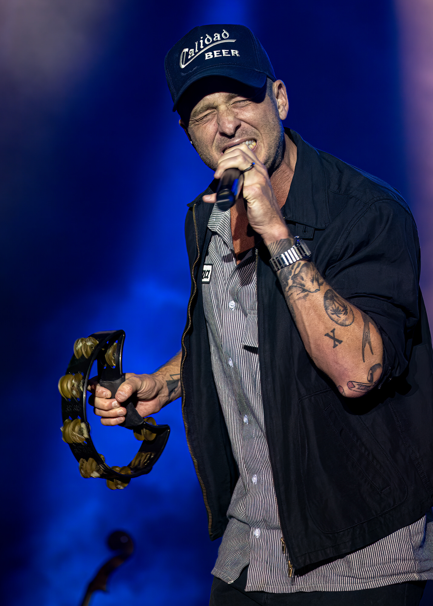 Singer with a tambourine under blue stage lights