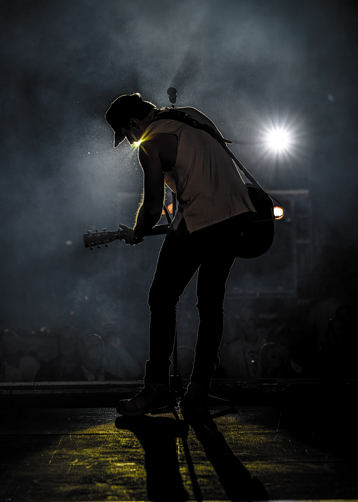 Guitarist silhouetted against a spotlight
