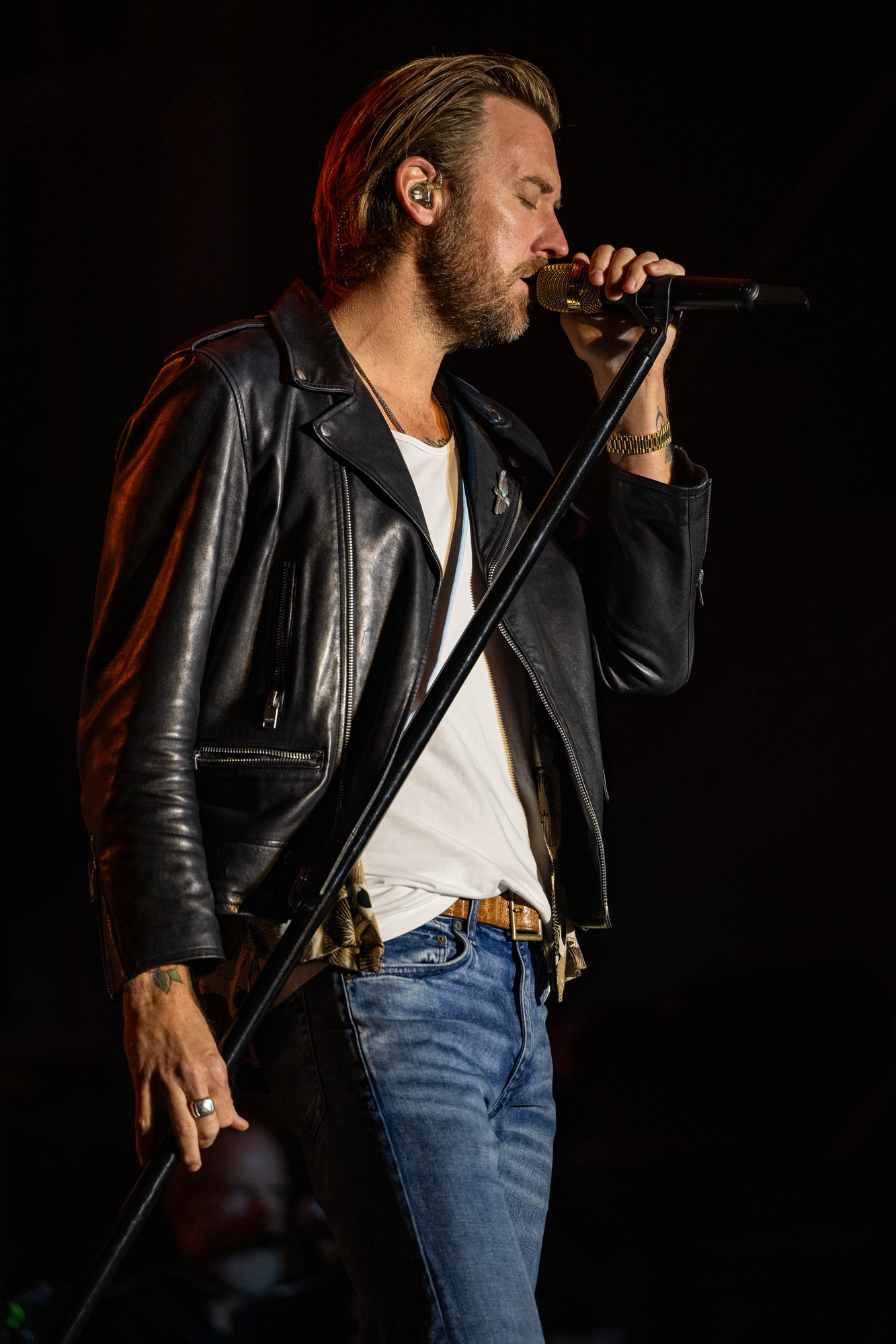 Singer in a leather jacket performing under a spotlight