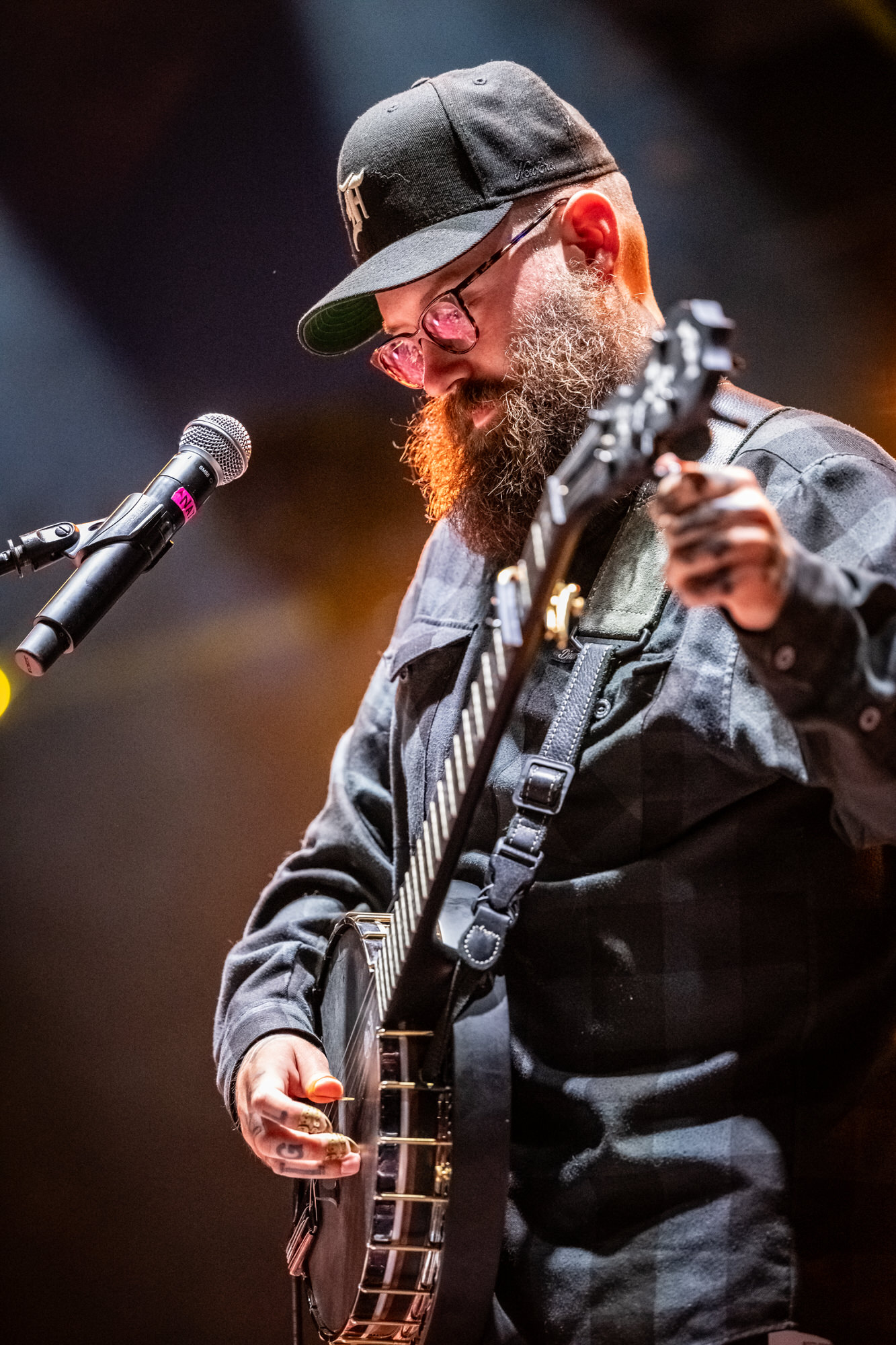 Bearded musician in a cap playing banjo at the microphone