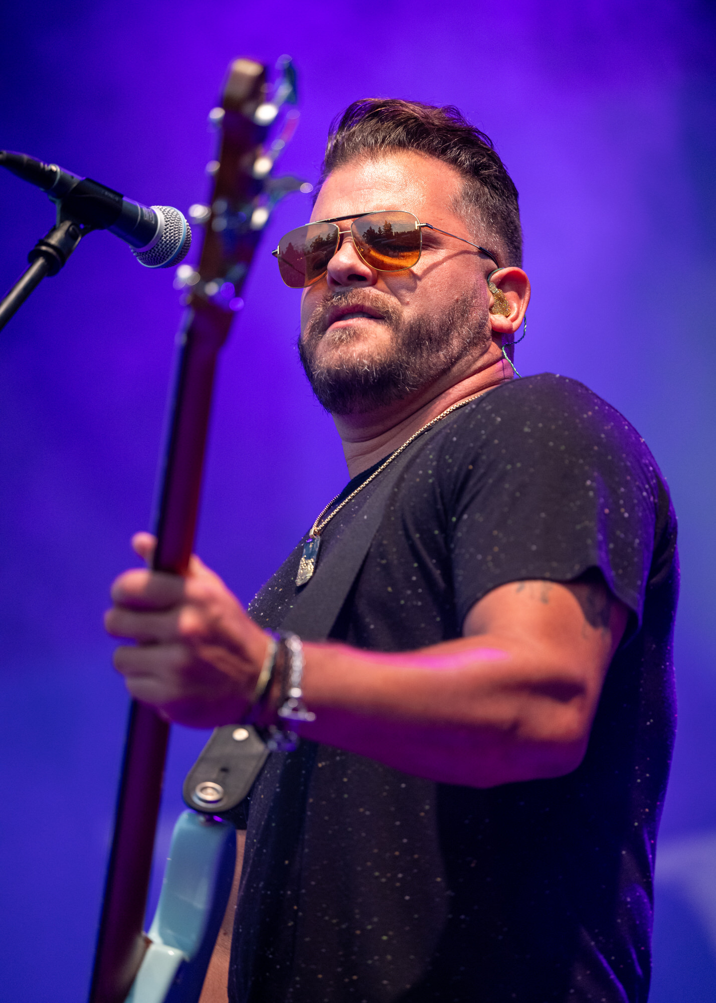 Guitarist in sunglasses at the microphone under purple stage light