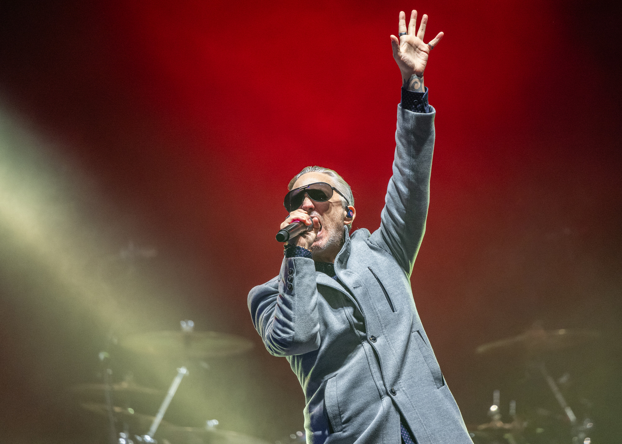 Singer raising a hand to the crowd in red stage light