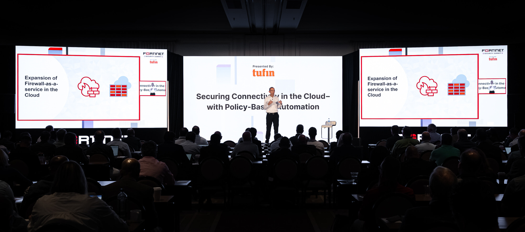 Main stage at a corporate conference, wide view of the audience and screens