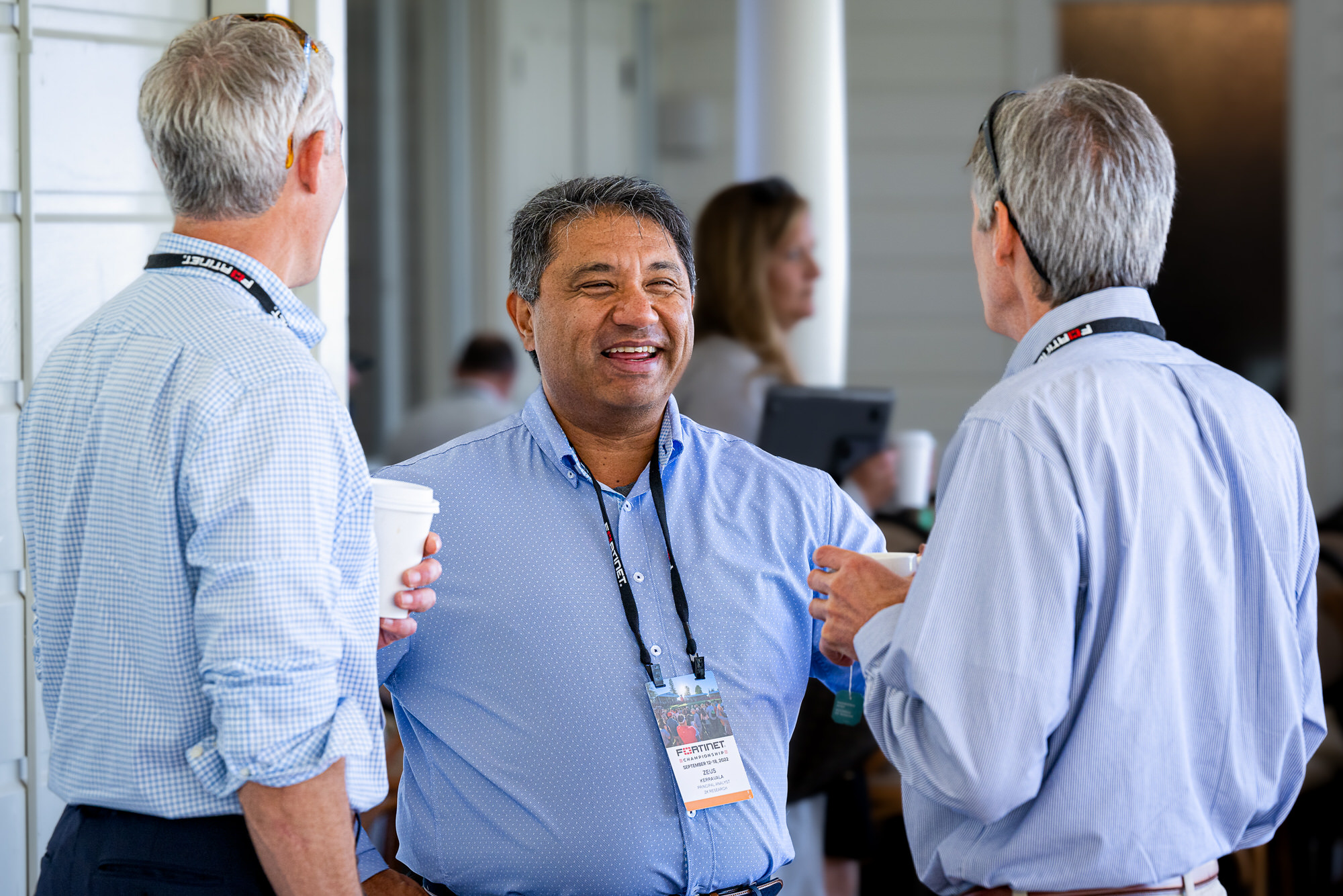 Three attendees laughing together over coffee between sessions