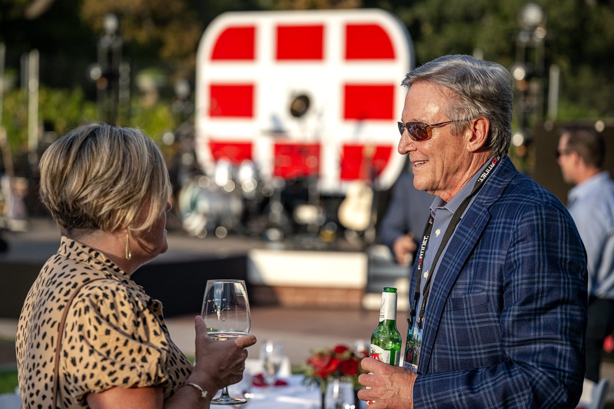Two guests talking over drinks at an outdoor reception
