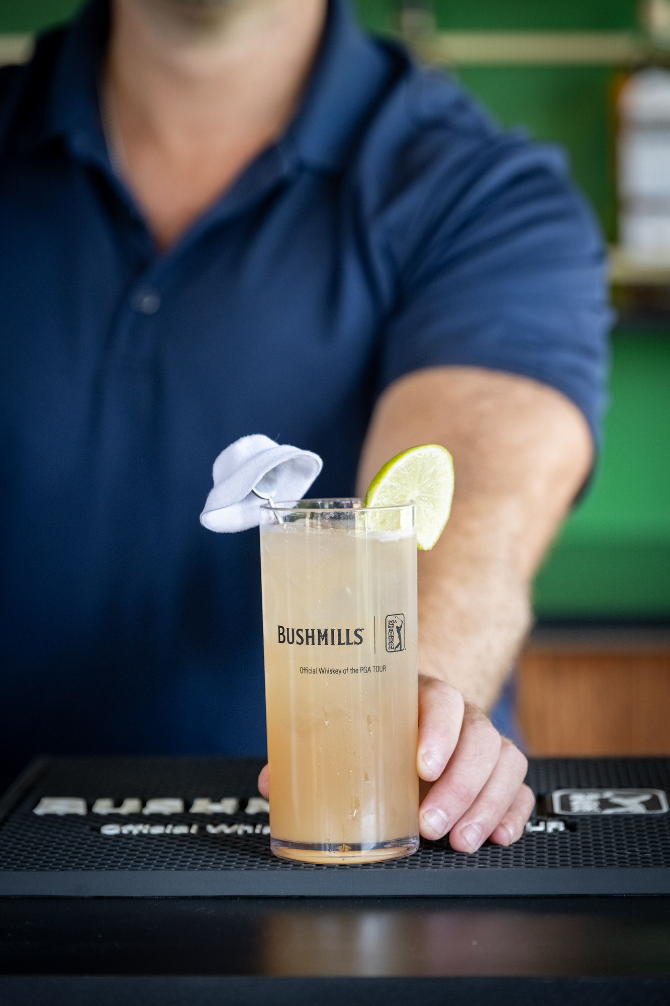 Bartender setting down a signature cocktail on a branded bar mat