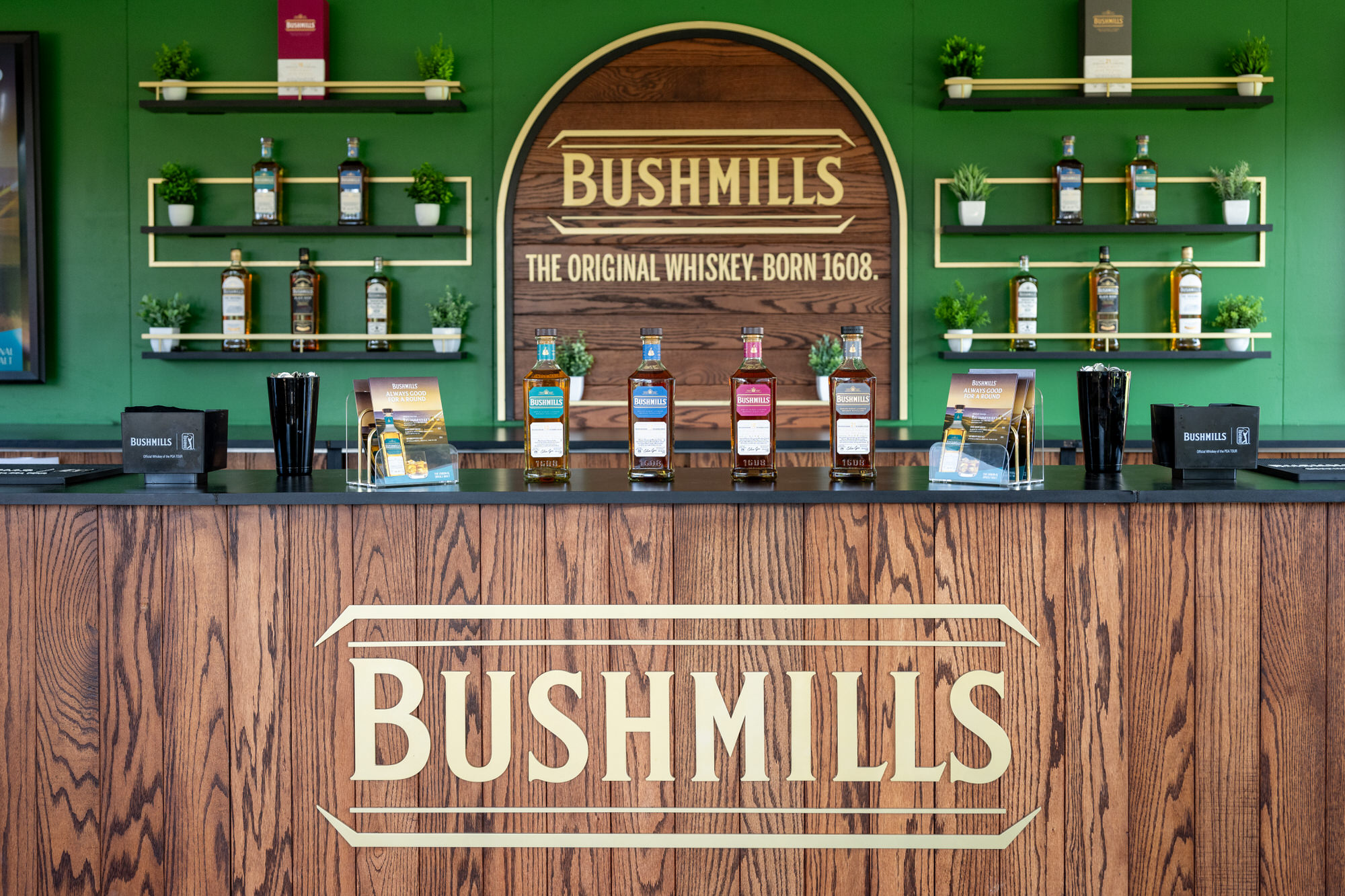 Branded whiskey bar with a carved wood front and green shelving