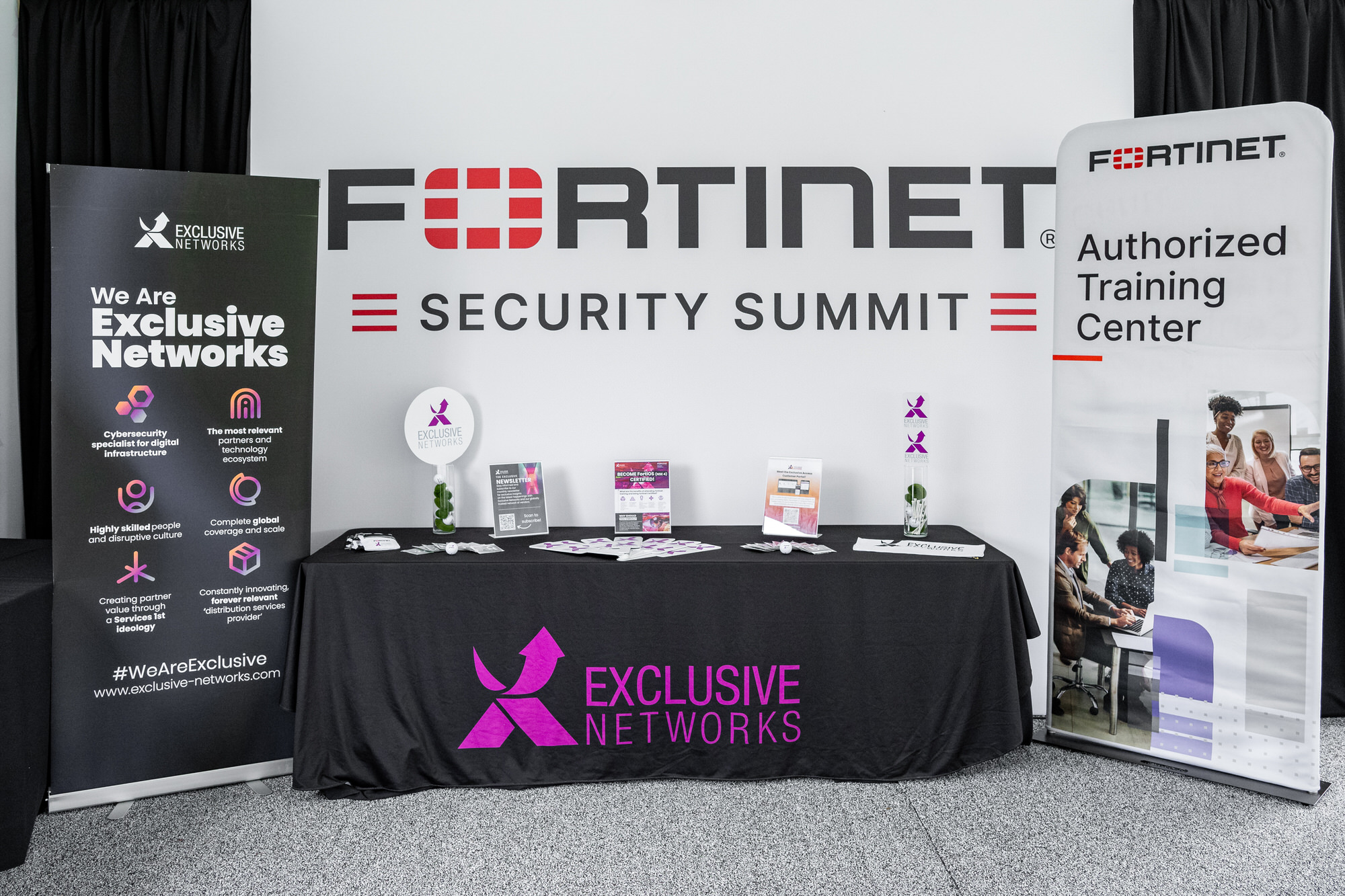 Sponsor exhibit table with pull-up banners in front of a conference backdrop