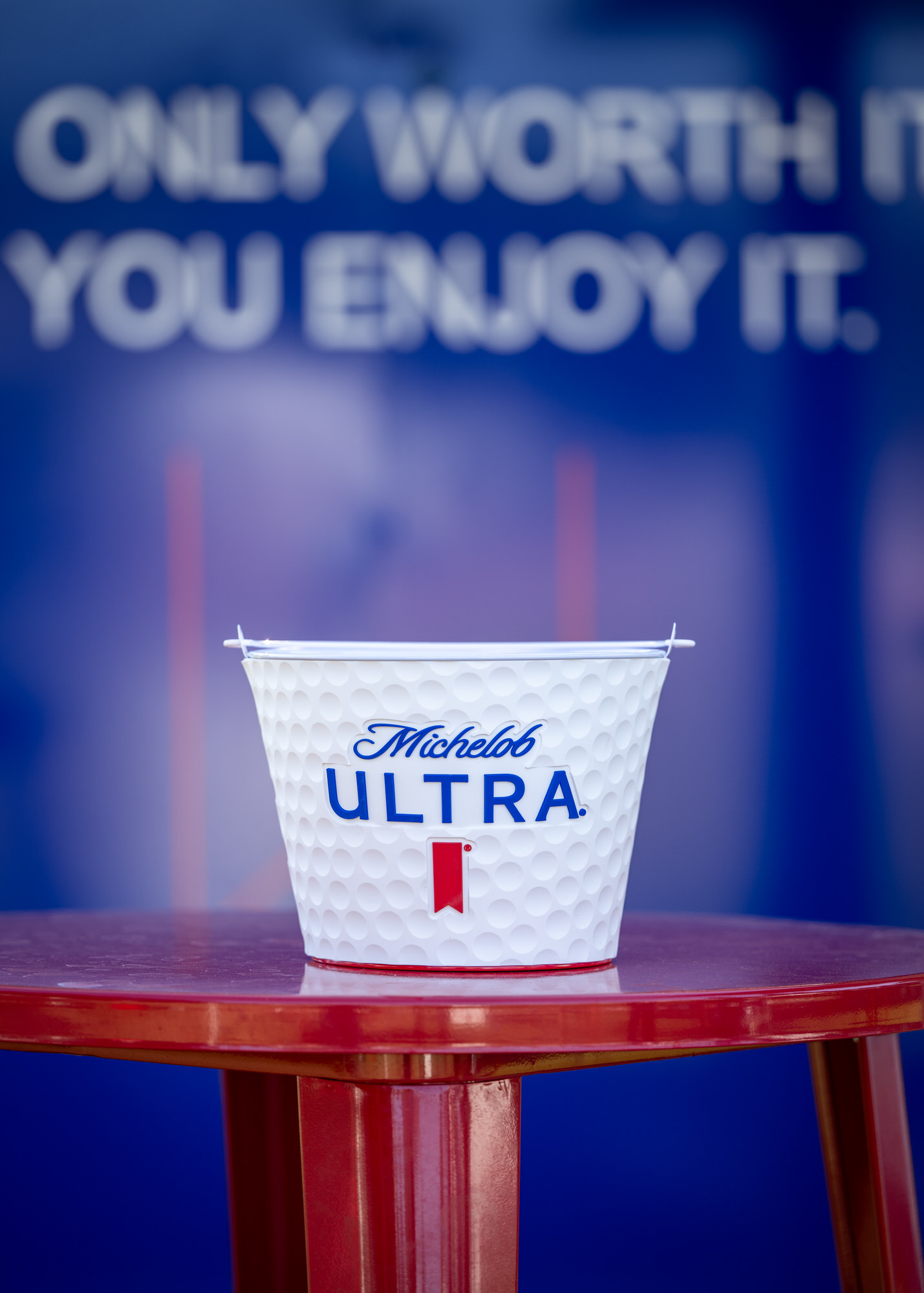 Branded ice bucket on a red cocktail table in a sponsor lounge