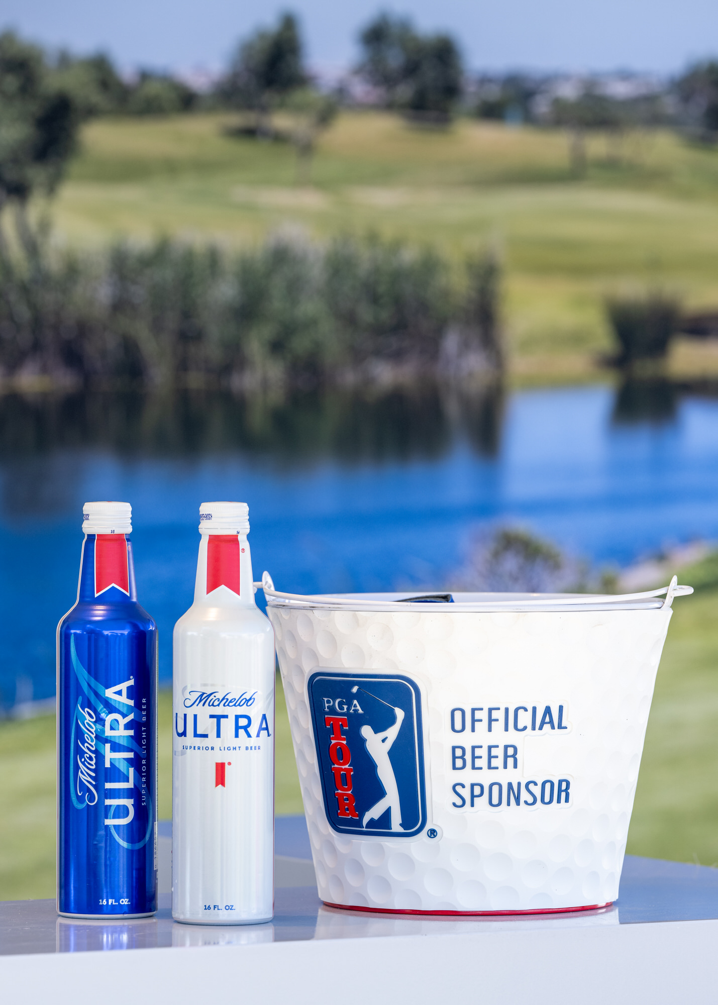 Sponsor bottles and a branded ice bucket overlooking a golf course lake