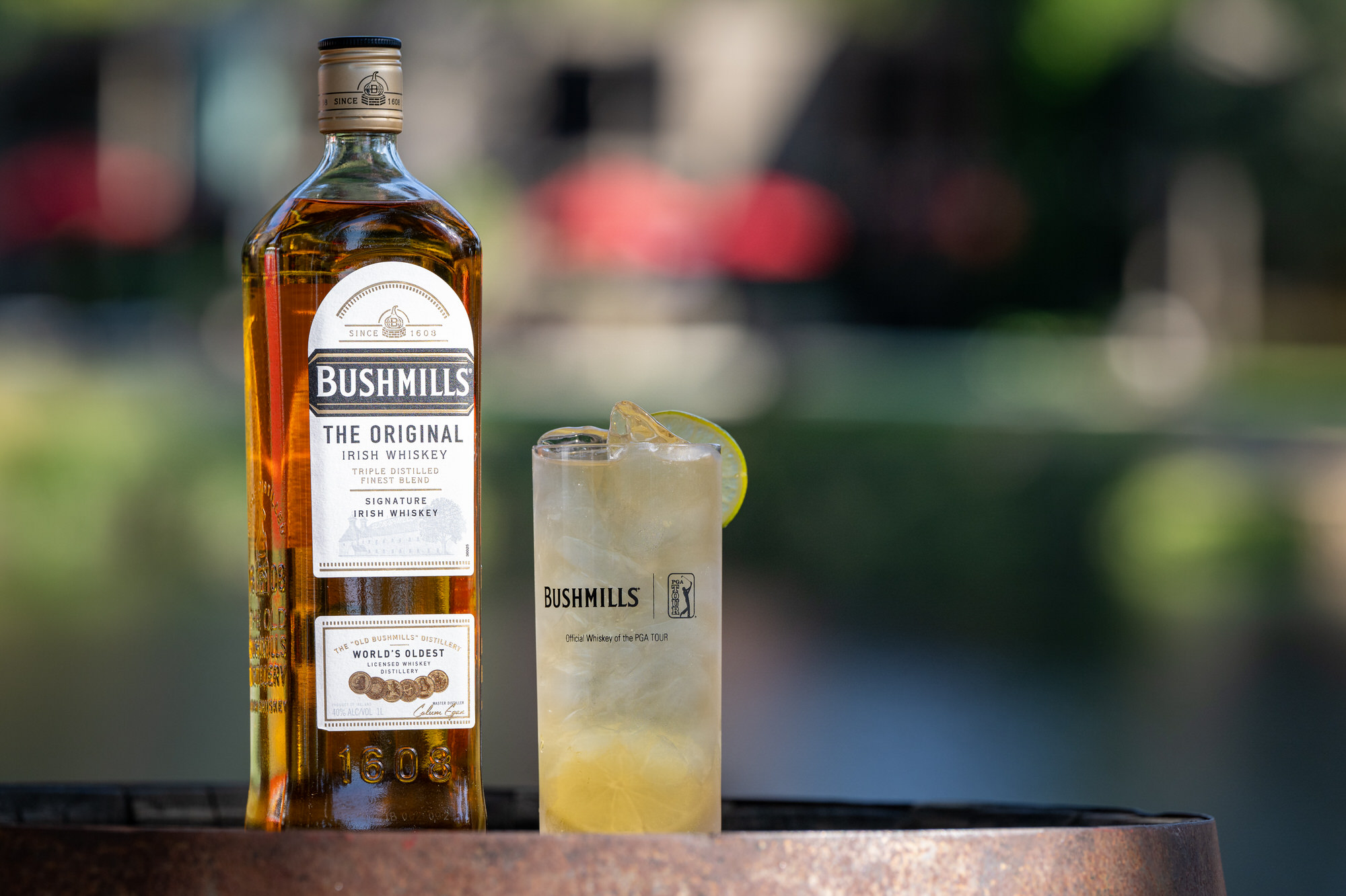 Whiskey bottle and a highball on a barrel top at a sponsor bar