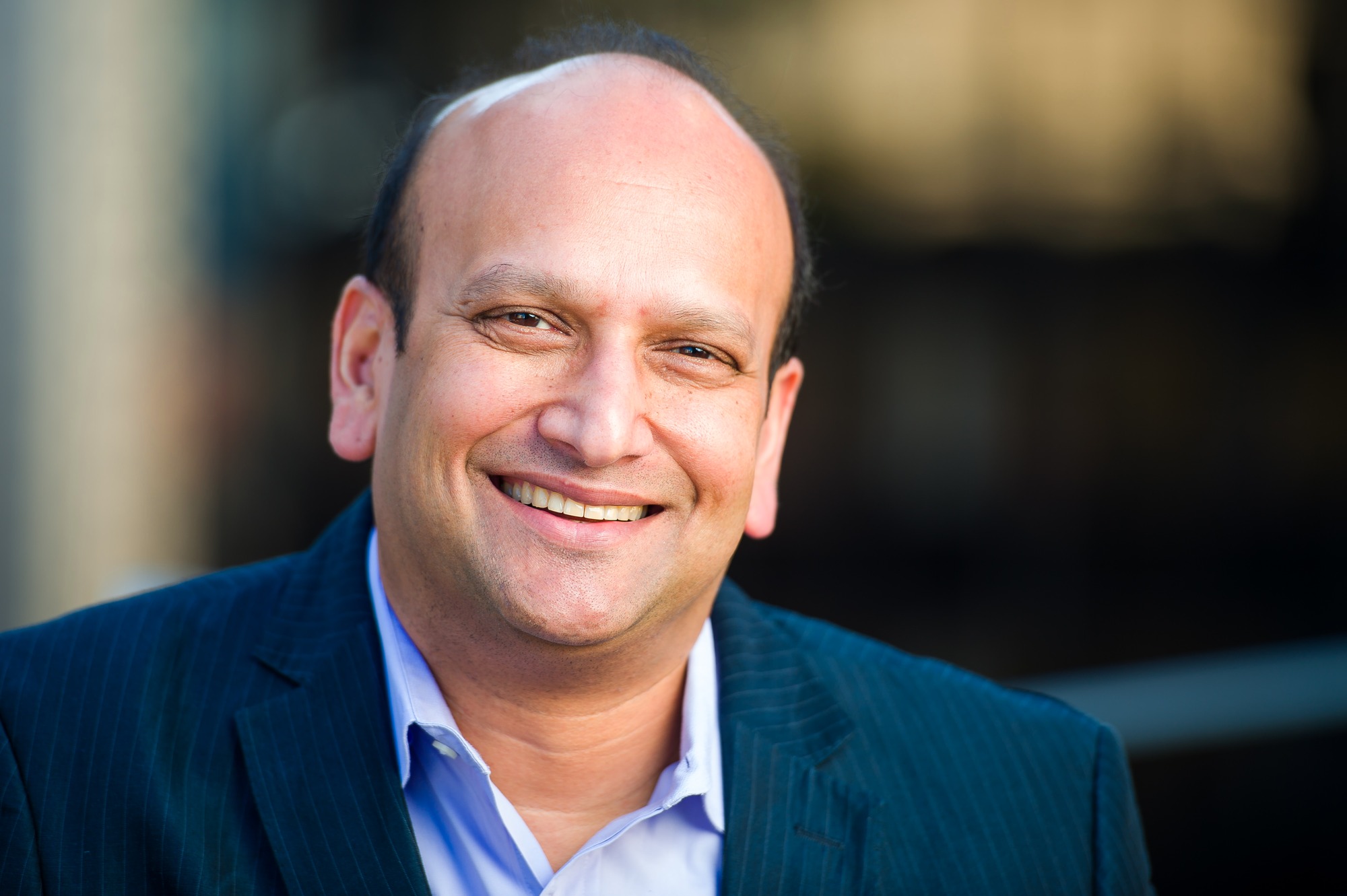 Executive headshot of a smiling man in a dark suit jacket