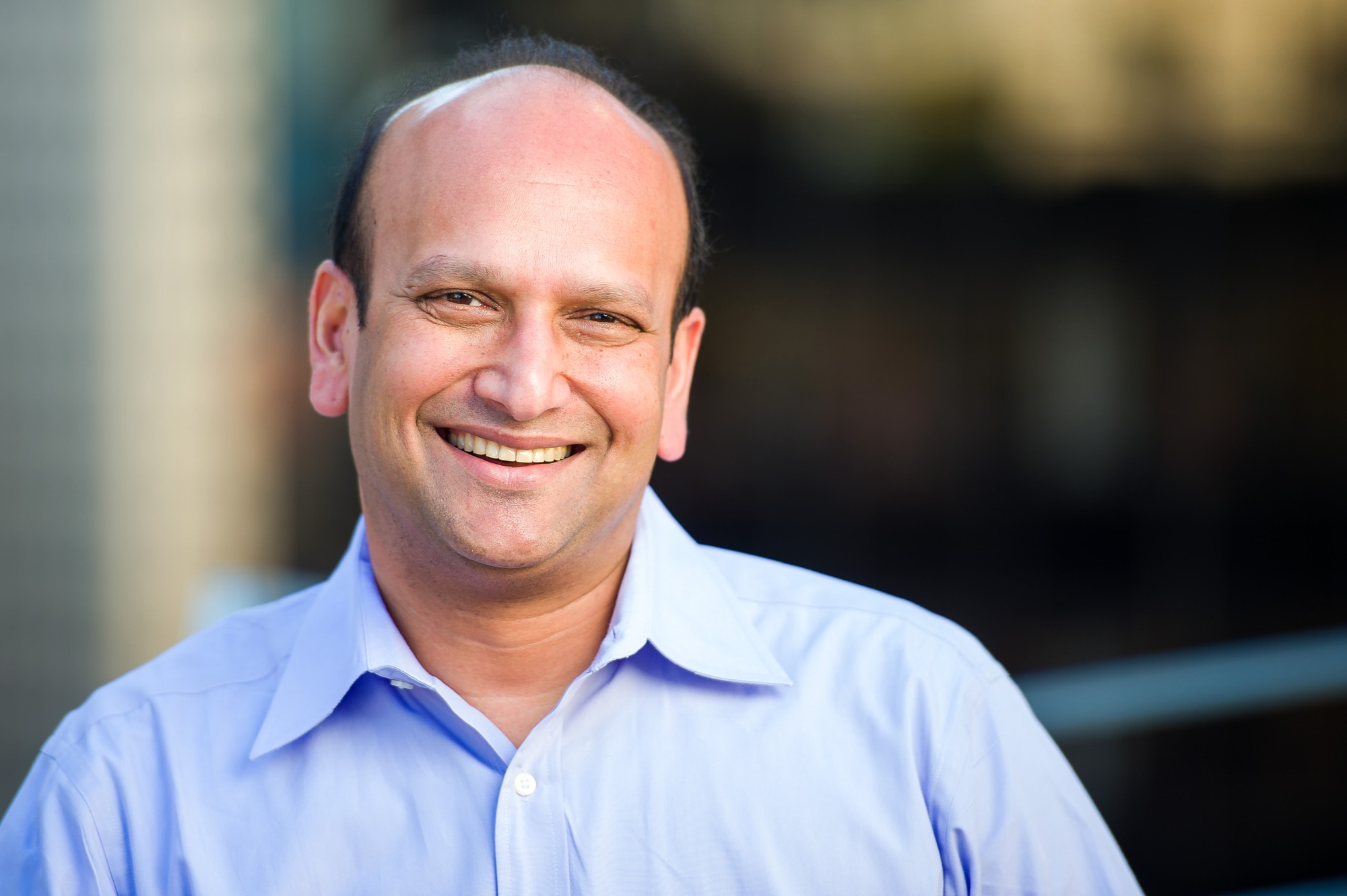 Corporate headshot of a smiling man in a light blue shirt
