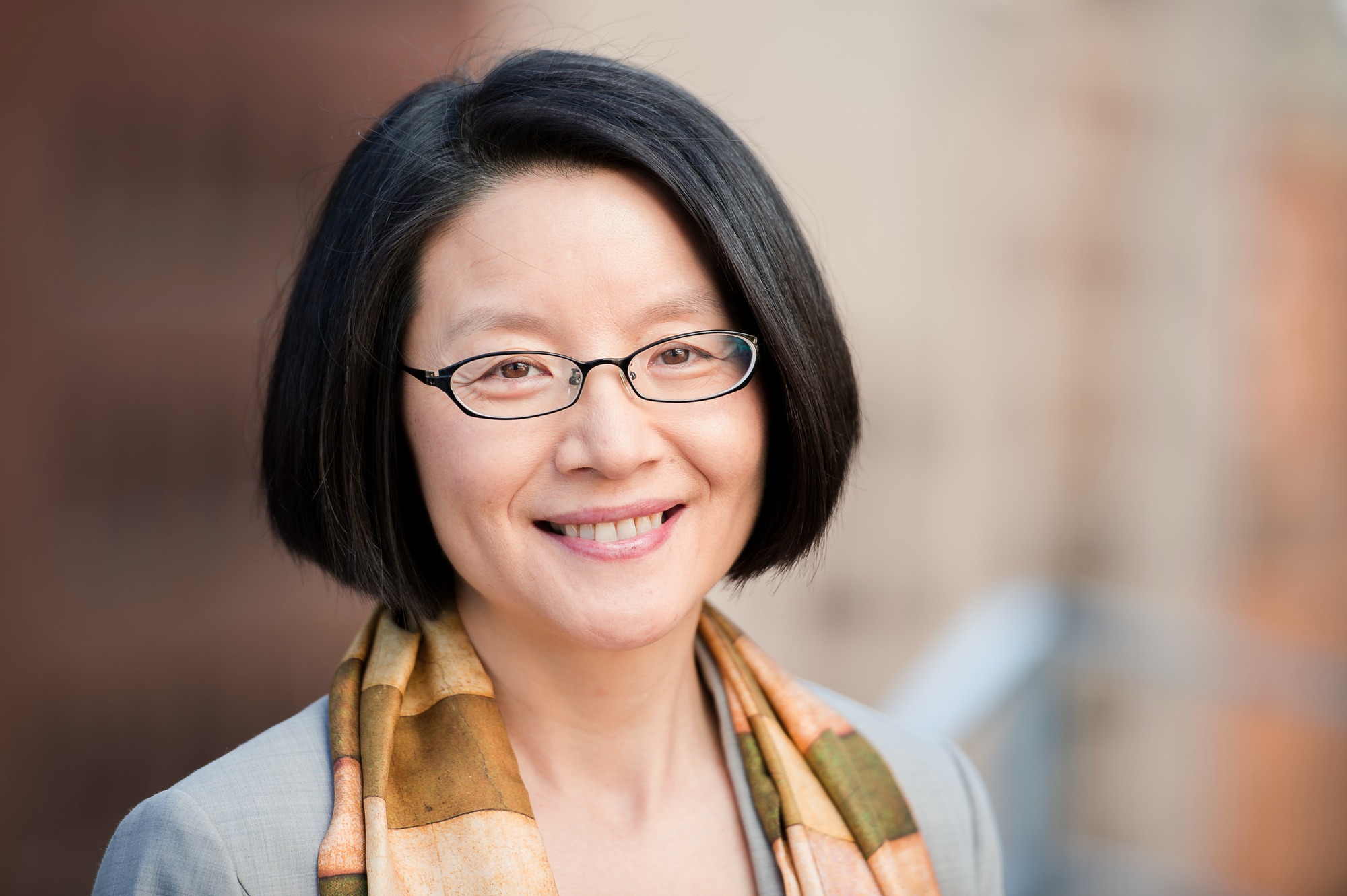 Corporate headshot of a woman with glasses and a patterned scarf