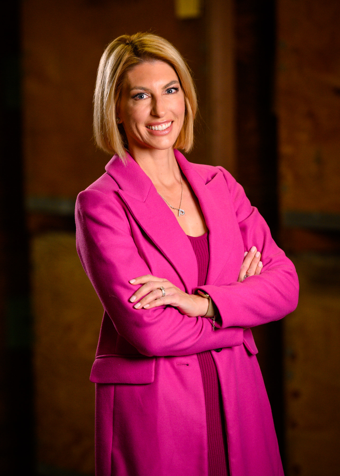 Executive portrait of a woman in a pink suit with arms crossed