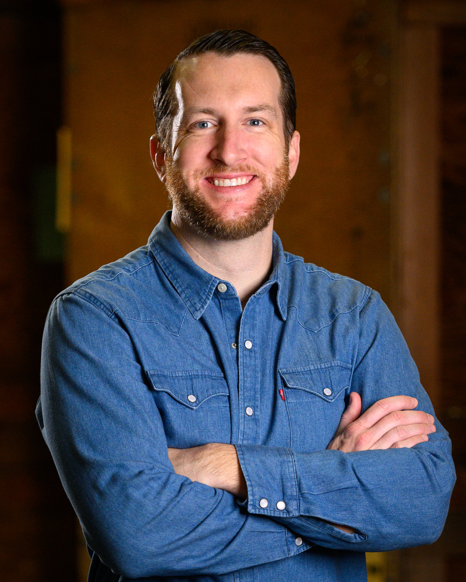 Portrait of a bearded man in a denim shirt with arms crossed