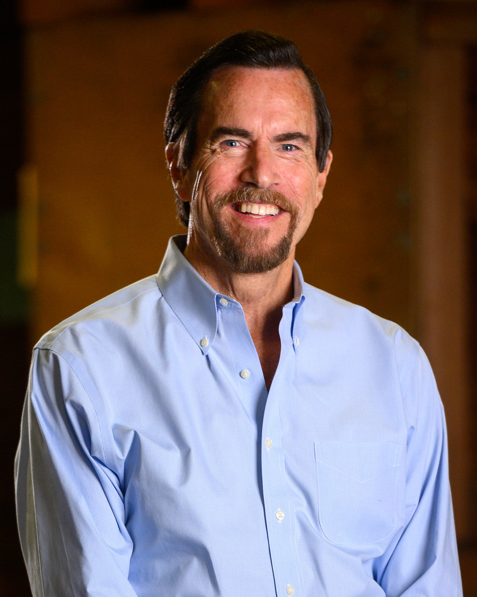 Portrait of a smiling man with a goatee in a light blue shirt