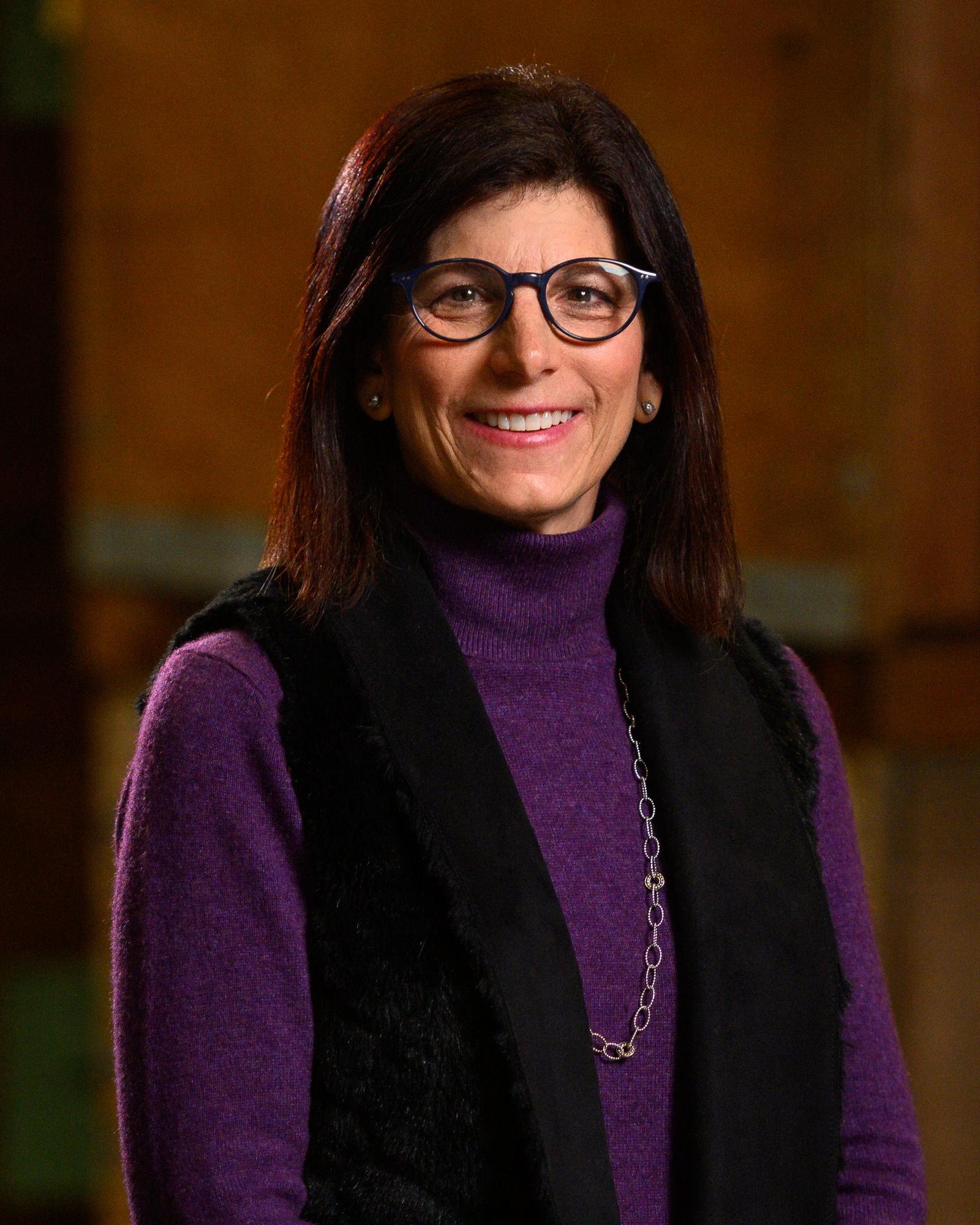 Portrait of a woman with glasses in a purple sweater and black vest